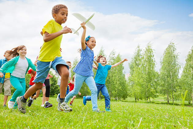 Happy girl holding airplane toy and children near