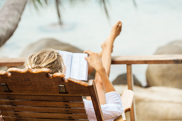 Young woman reading a book while relaxing on tropical island