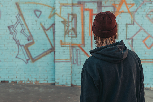 rear view of man looking at colorful graffiti on wall